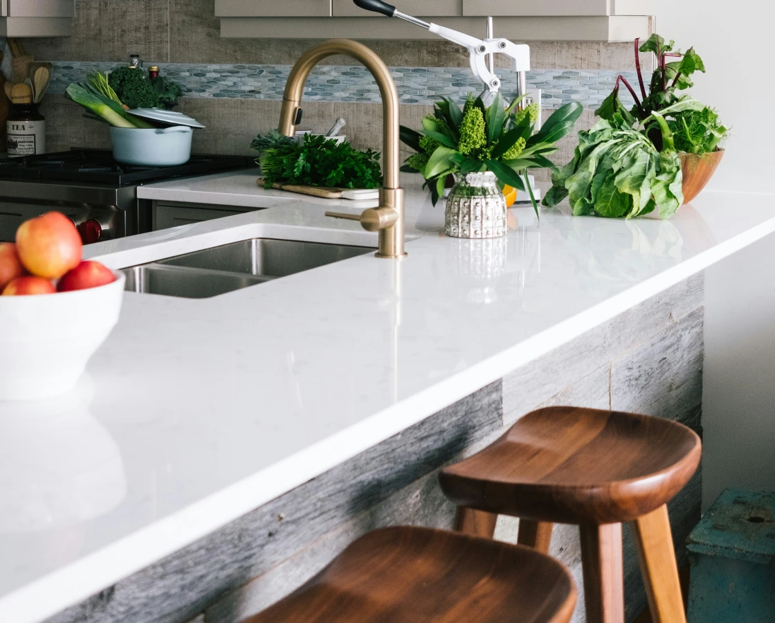 White kitchen island with brass faucet and stools